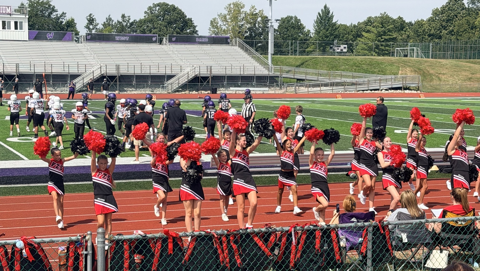 Junior Bulldogs cheerleaders performing with red and black pom-poms during a football game